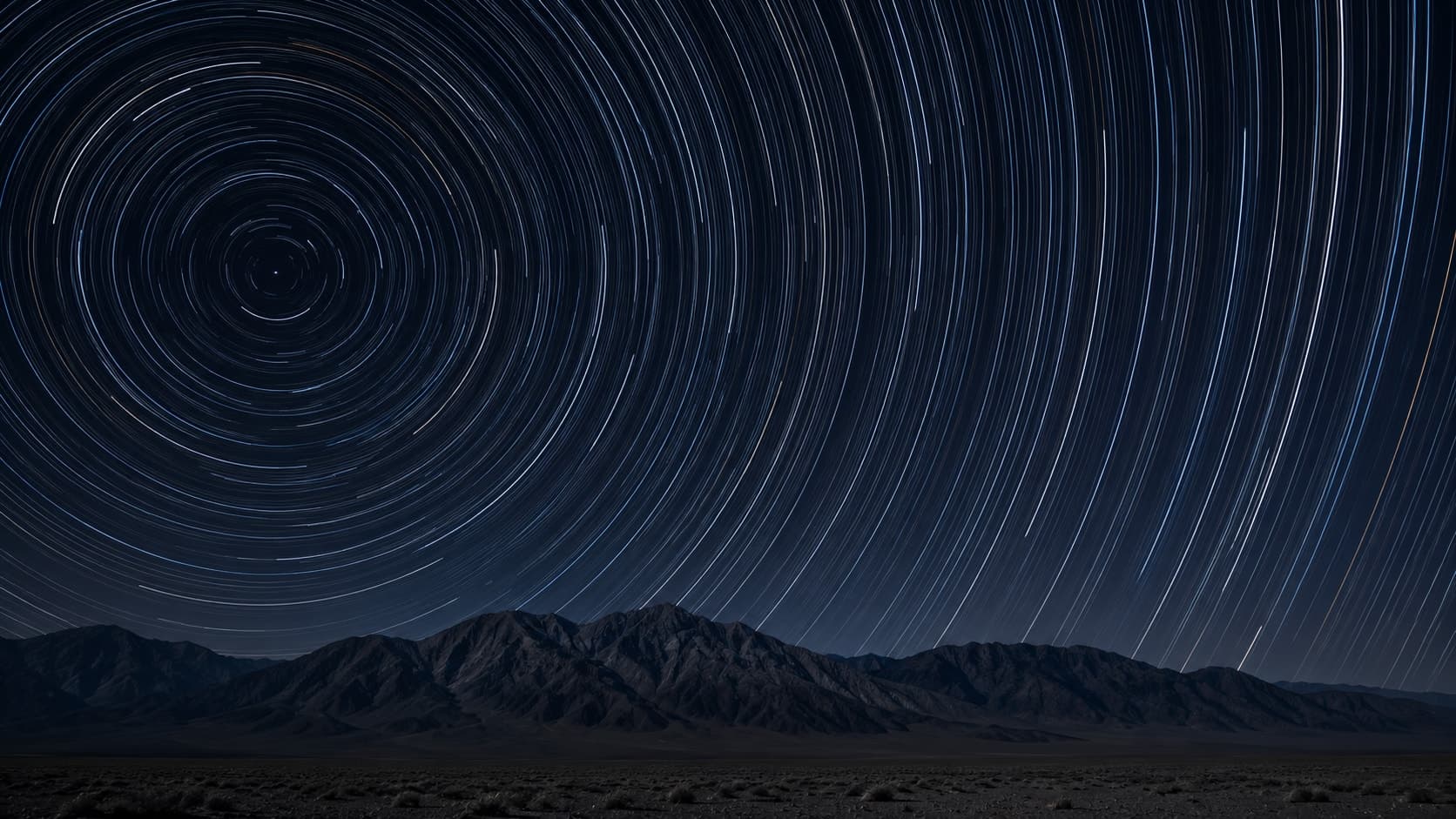 Concentric circumpolar star trails wheeling above the ridgeline in a very long exposure.